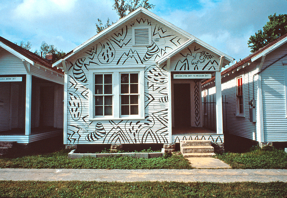 Photograph of a small row house painted with crude but rhythmic shapes, from the first exhibition at Project Row Houses in Houston.