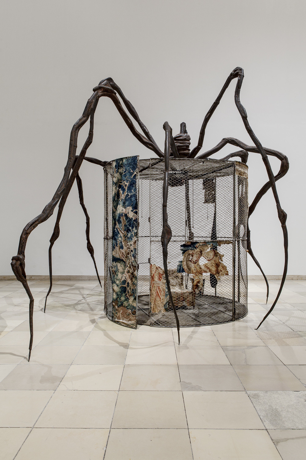 Large cylindrical cage with some tapestries on the walls, and wavy spider legs coming out of the top down to the floor.