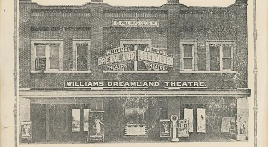Faded black and white photograph of a brick building with the a sign reading Williams Dreamland Theatre on the front. A box office and movie posters are visible.