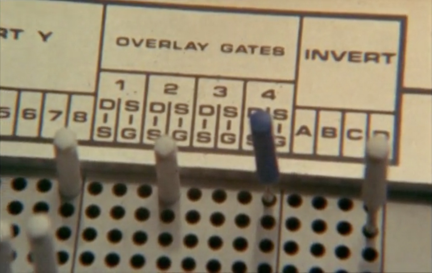 Analog electronic equipment 
			of some kind with words 'overlay gates' and 'invert' printed above gride of holes, a few filled with pegs.