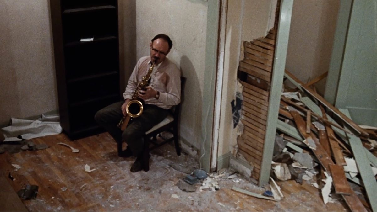 A man playing saxophone in a room that has been ripped apart
